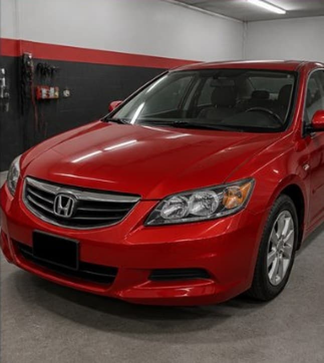 Red sedan with a dented hood and bumper, after repair