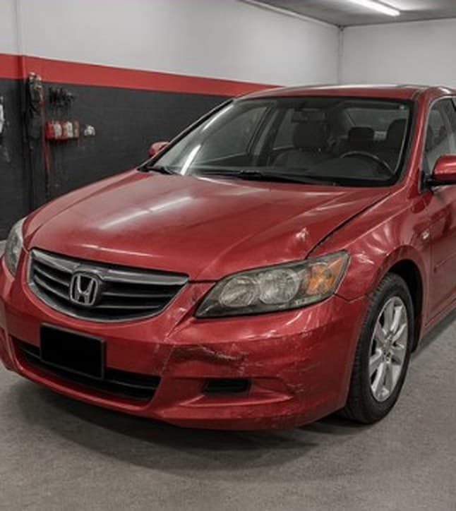 Red sedan with a dented hood and bumper, before repair