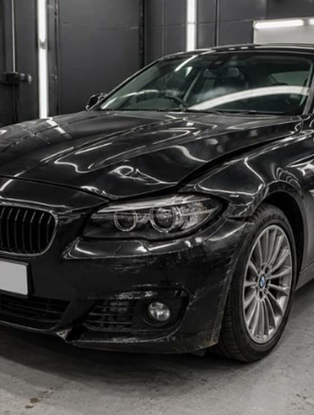 Black sedan with front-end damage, before repair